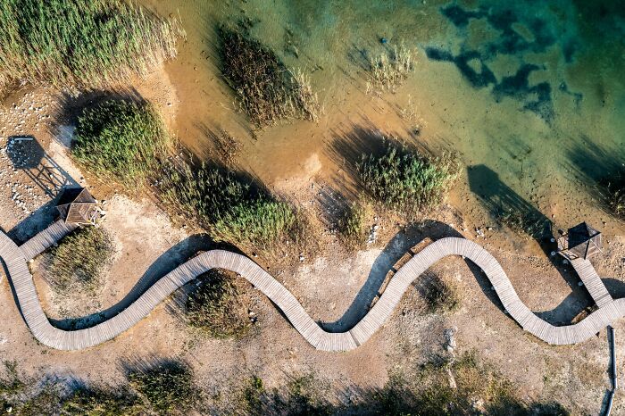 An aerial view of a winding boardwalk along a lakeshore, showing the effects of the brutal drought on the water levels.