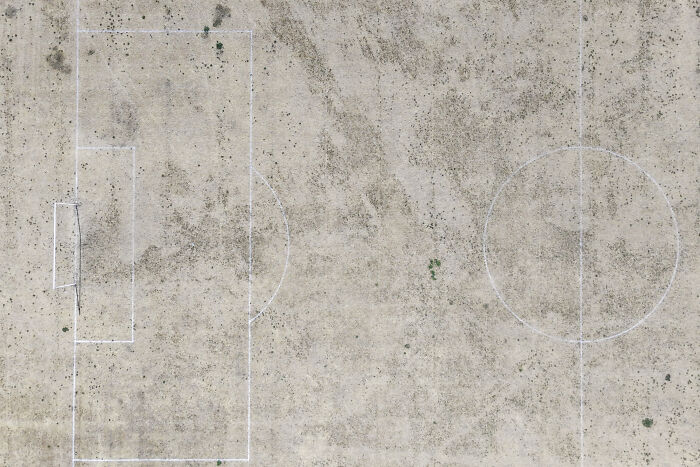 Aerial view of a dry, cracked football field, suffering from Europe's brutal drought.