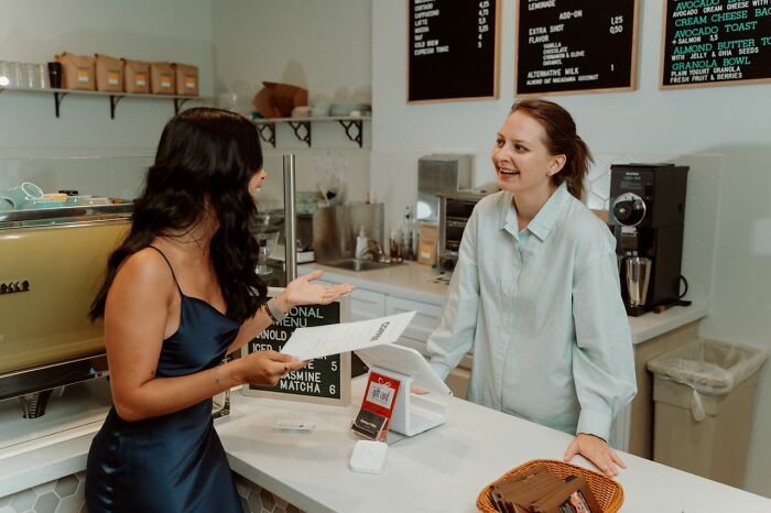 Two women smiling and talking at a counter, possibly discussing questions Americans asked Europeans.