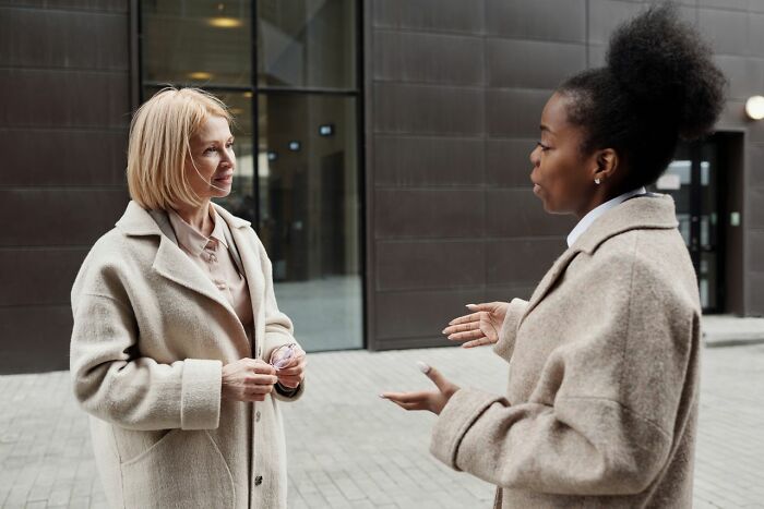 Two women in coats having a conversation, like Europeans discussing questions Americans asked them.