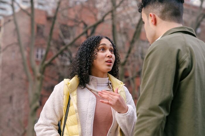 A woman with curly hair looking surprised while talking to a man, illustrating questions Americans asked Europeans.