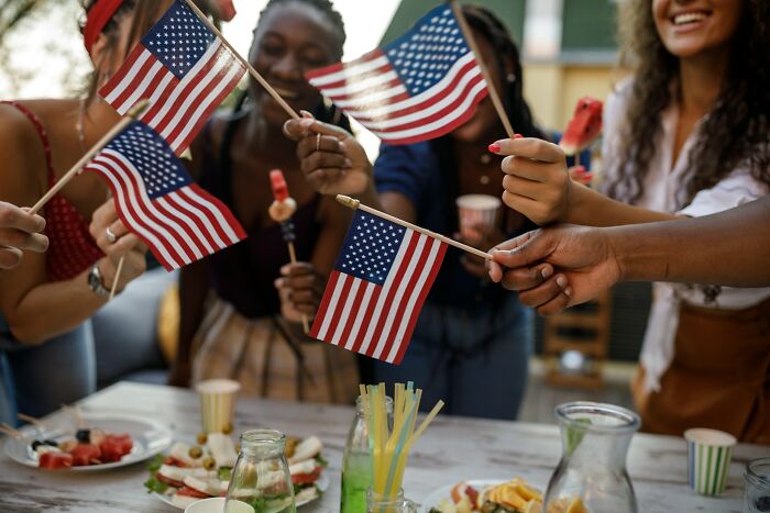 Americans at a gathering holding small American flags, reflecting on surprising questions Americans asked Europeans.
