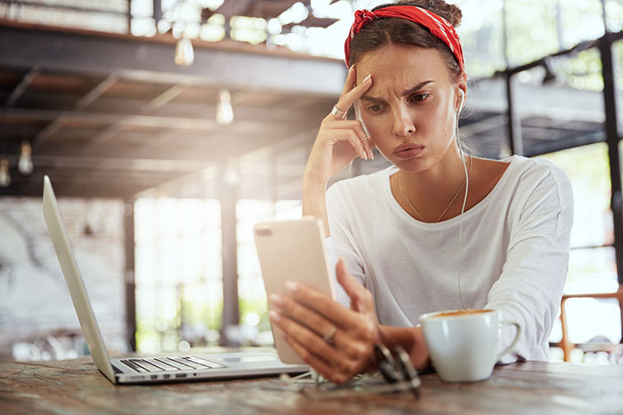 A displeased woman looking at her phone, upset about her boyfriend's comment on her hair color.