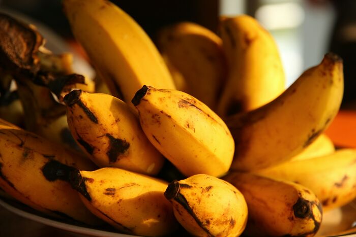 A close-up shot of a bunch of ripe bananas on a plate, some with brown spots, related to questionable Instacart shopper selections.
