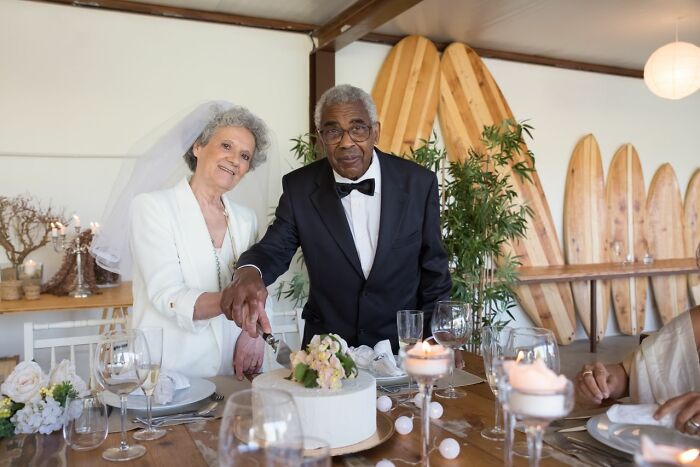 Elderly couple happily cutting wedding cake, showing people in their lives can find new beginnings.