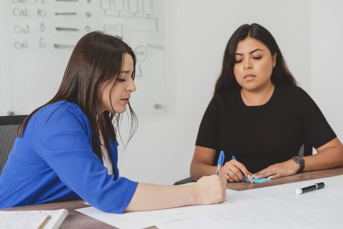 Two women collaborating at a table, discussing aspects of people in their lives they can’t respect anymore.