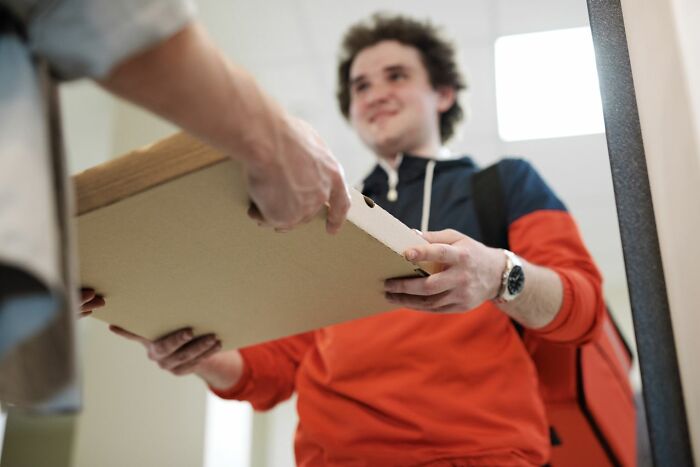 A smiling man receiving a pizza box, considering people in his life he can't respect anymore.
