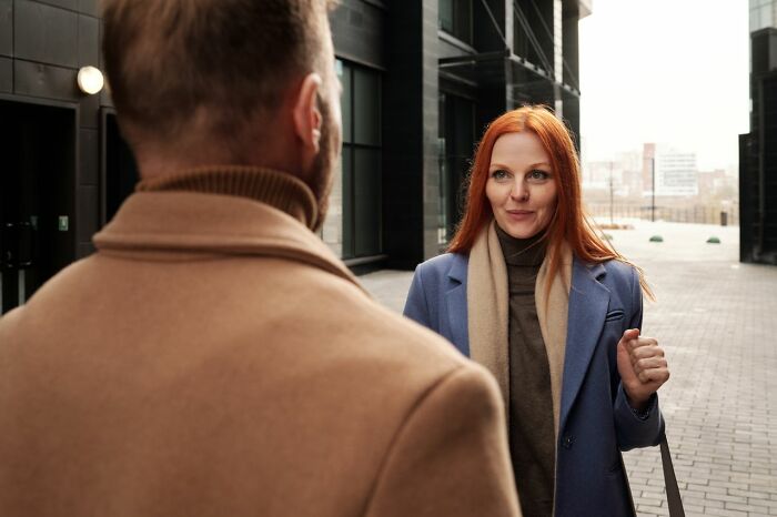 Woman with red hair talking to a man outdoors, representing interactions with people in their lives.