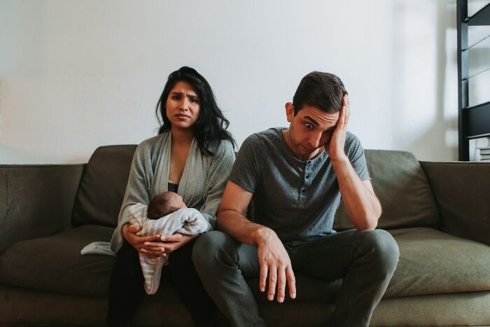 Stressed parents with a baby on a couch, reflecting how people in their lives face new challenges.