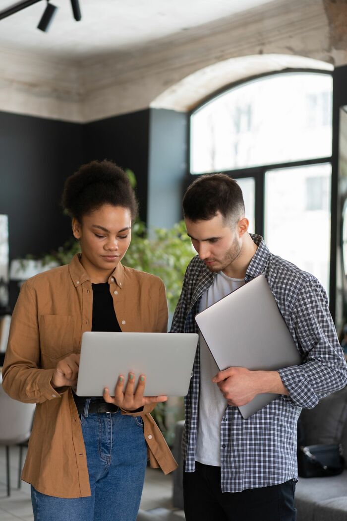 A woman and a man looking at a laptop, related to ways women shut down creepy men.