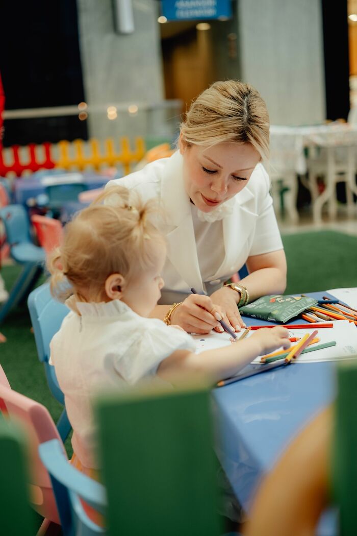 Woman and child coloring together at a table. This image illustrates the savage ways women shut down creepy men.