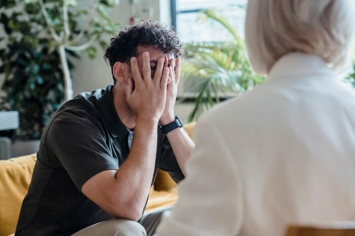 A man looking distressed with his hands covering his face, in a scene about women who shut down creepy men.