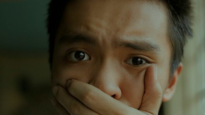 A man's close-up face with wide eyes and a hand covering his mouth. Many women shut down creepy men.
