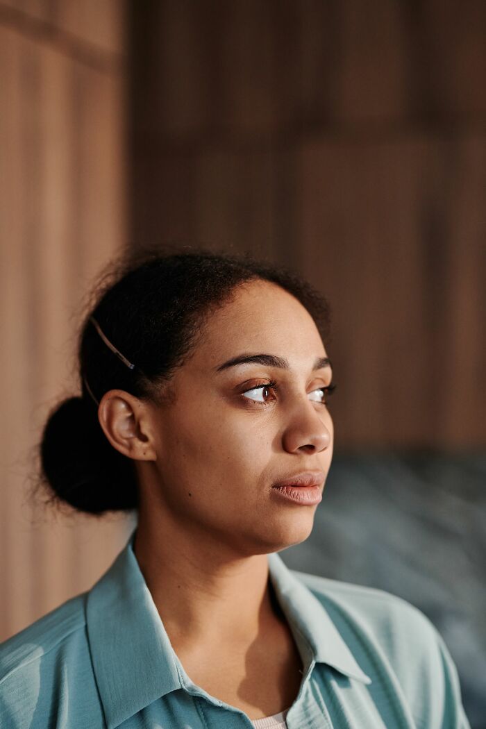 A contemplative woman looking away, with a serious expression, embodying the strength of women.