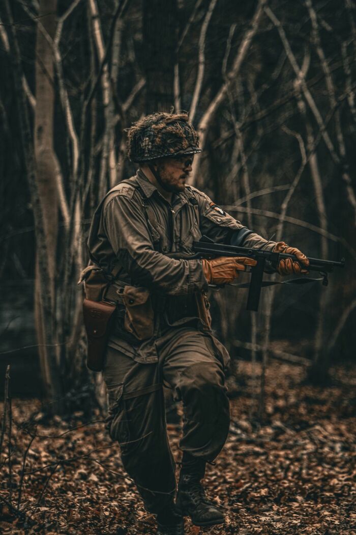 Soldier in a camouflage helmet and uniform holding a rifle in a forest. This image illustrates the savage ways women shut down creepy men.