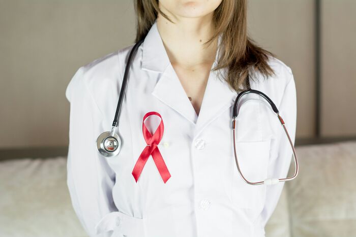 Doctor in a white coat with a red ribbon, symbolizing cancer awareness and the challenges of cancer med side effects. Doctor in a white coat with a red ribbon, symbolizing cancer awareness and the challenges of cancer med side effects.