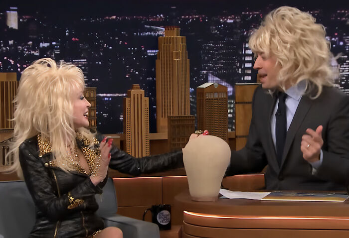 Dolly Parton on a talk show, discussing her real hair and iconic wigs, revealing her natural look to fans. Dolly Parton on a talk show, discussing her real hair and iconic wigs, revealing her natural look to fans.