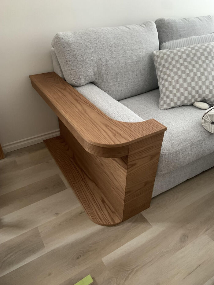 A DIY home project: a sleek wooden armrest extension for a gray couch, transforming a space with a small budget.