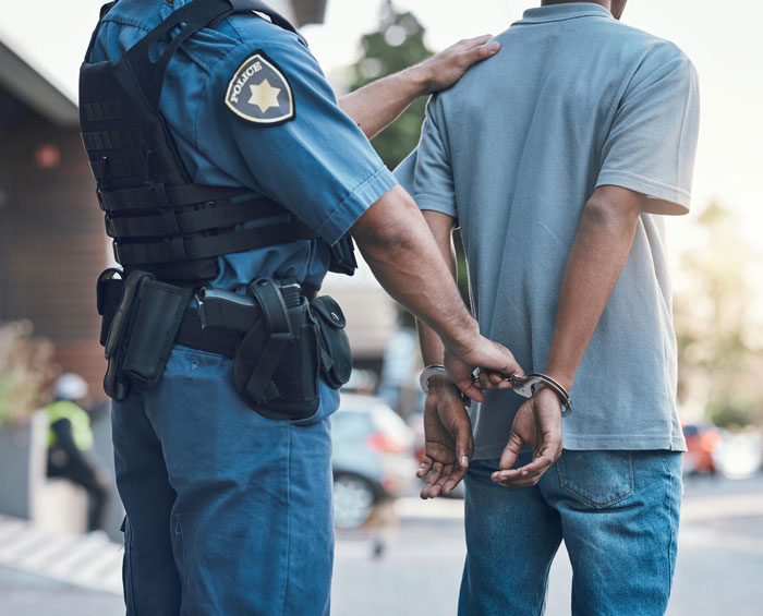 Police officer arresting a person in handcuffs, representing evidence of theft and the manager firing incident. Police officer arresting a person in handcuffs, representing evidence of theft and the manager firing incident.