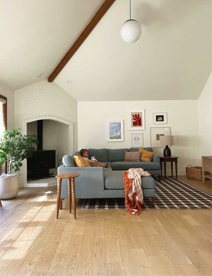 A spacious living room home design with a light blue sectional sofa, a fireplace, and a large houseplant.