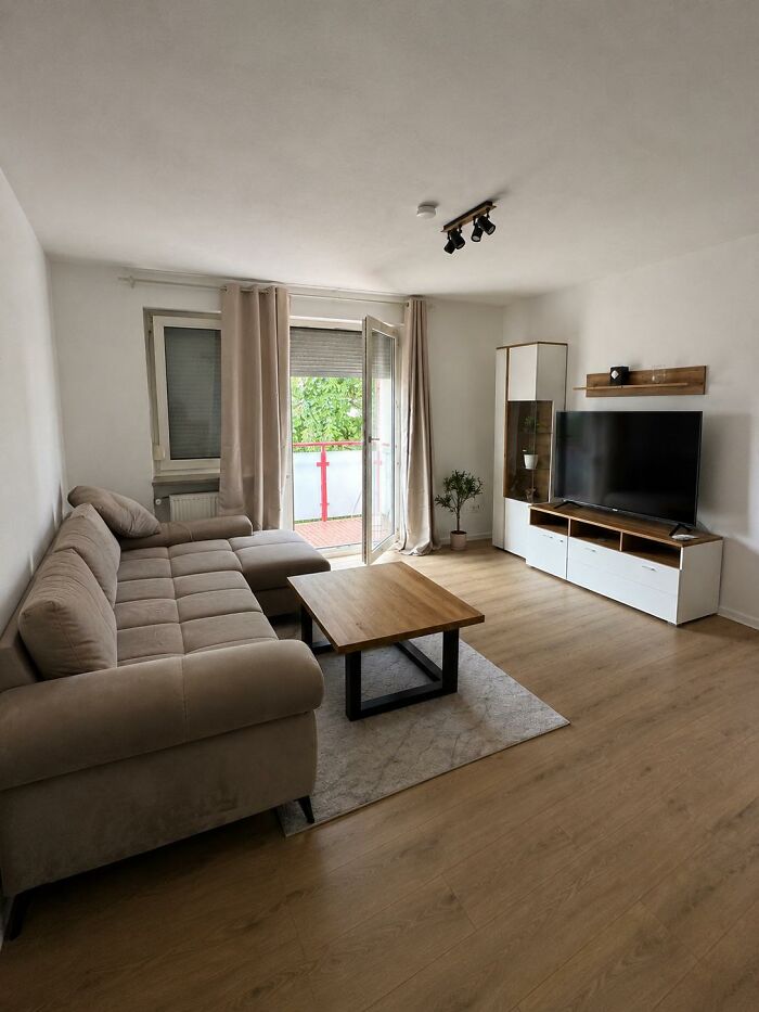 A modern living room home design with a large L-shaped sofa, a wooden coffee table, and a flat-screen TV.