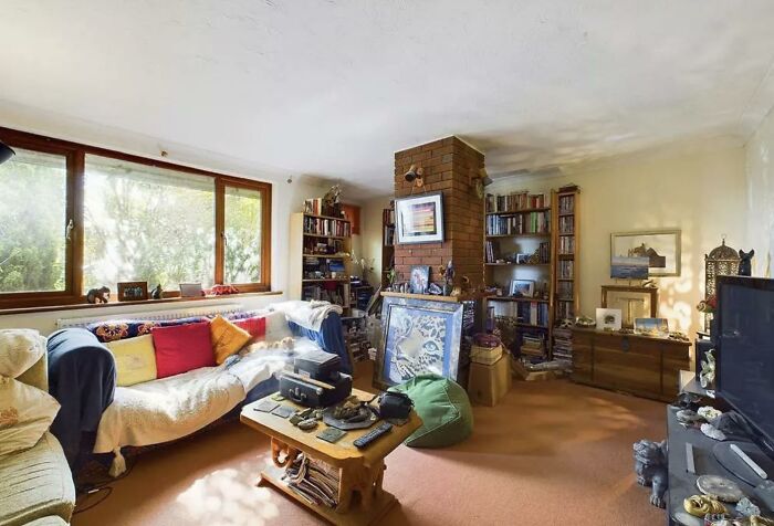 A cozy living room packed with eclectic home design choices, including a brick pillar, bookshelves, and various decor items, for honest opinions.