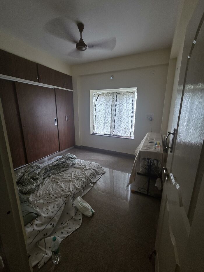 A bedroom with dark wooden closets and a patterned curtain, displaying personal home design choices.