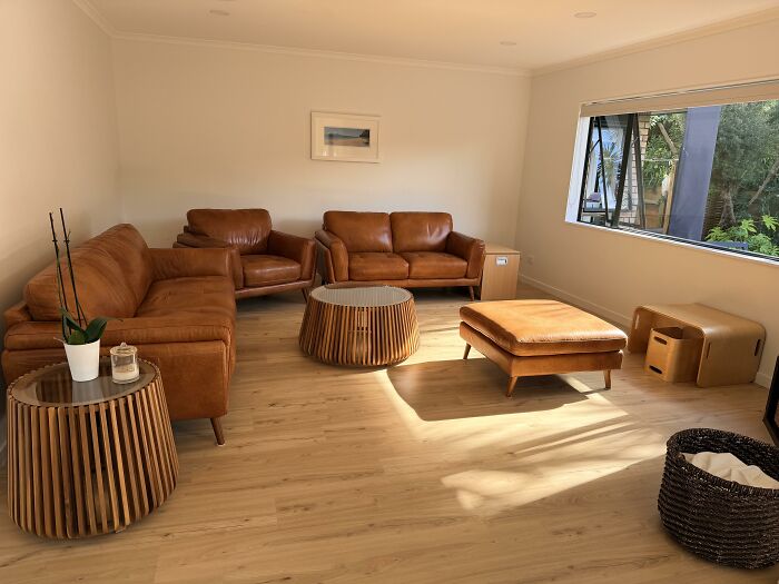 A living room featuring contemporary home design choices with leather sofas, wooden coffee tables, and light flooring, seeking honest opinions.