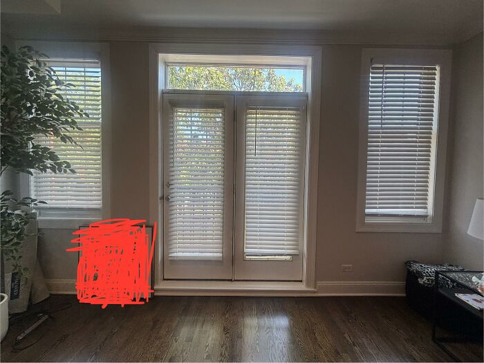 An empty room with french doors and two windows, showcasing home design choices for honest opinions.