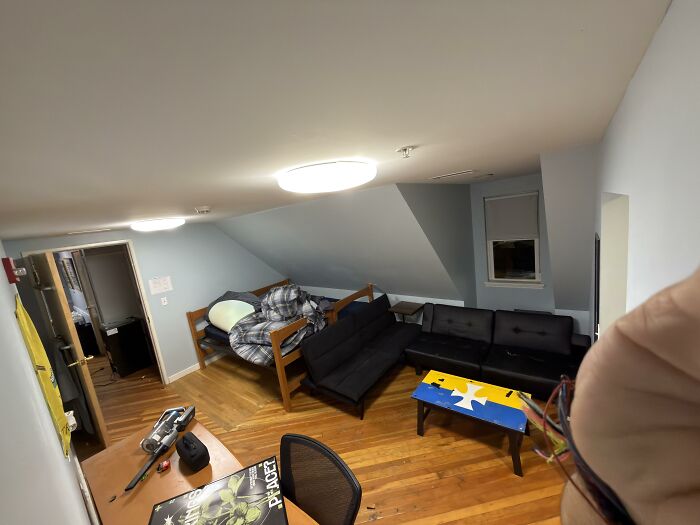 A bedroom with sloped ceilings, showcasing home design choices like a wooden bed and a dark sofa.