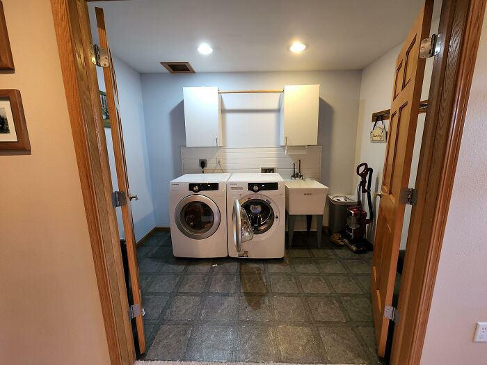 A laundry room displaying practical home design choices, featuring a washer, dryer, and utility sink.