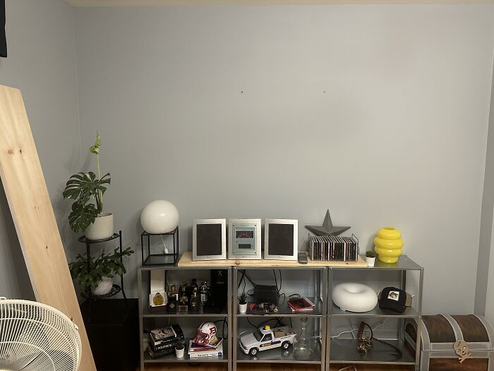 A wall unit with different home design choices and decor items, including plants and sound systems.