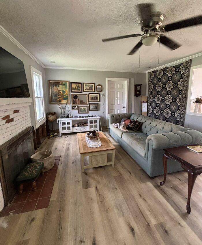 A cozy living room with various home design choices, including a patterned tapestry and a light blue sofa.