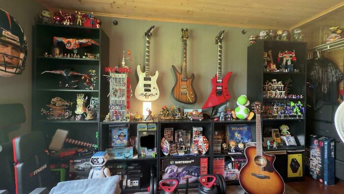 A room showcasing diverse home design choices, including three electric guitars, shelves filled with action figures, and video game memorabilia.