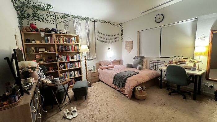A cozy bedroom with thoughtful home design choices, featuring a pink bed, a large bookshelf, and wall decorations.