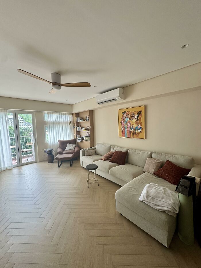 An airy living room with a light-colored sectional, wood floors, and balcony access, highlighting home design choices.