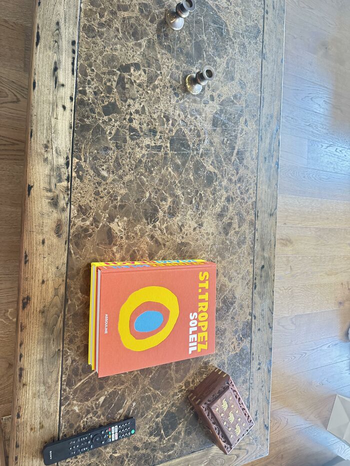 An overhead view of a rustic wooden coffee table with a St. Tropez Soleil book and small decorative items, part of home design choices.