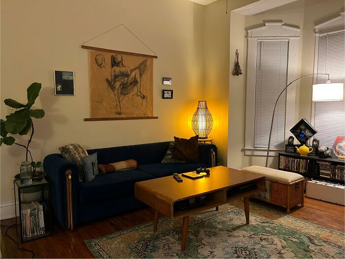 An inviting living room at night with a blue sofa, artistic wall decor, and ambient lighting, reflecting home design choices.