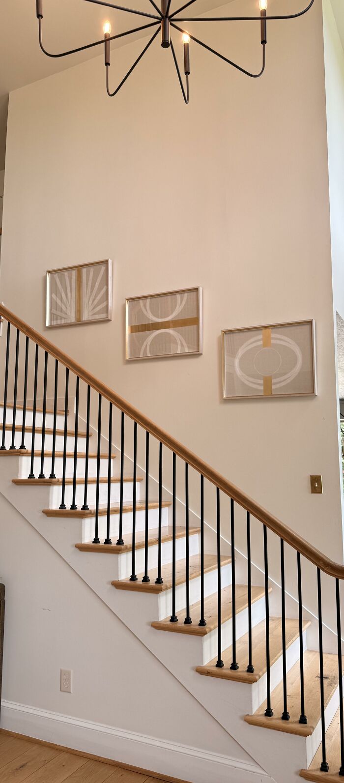 A modern staircase with black railings and three abstract artworks, highlighting home design choices.