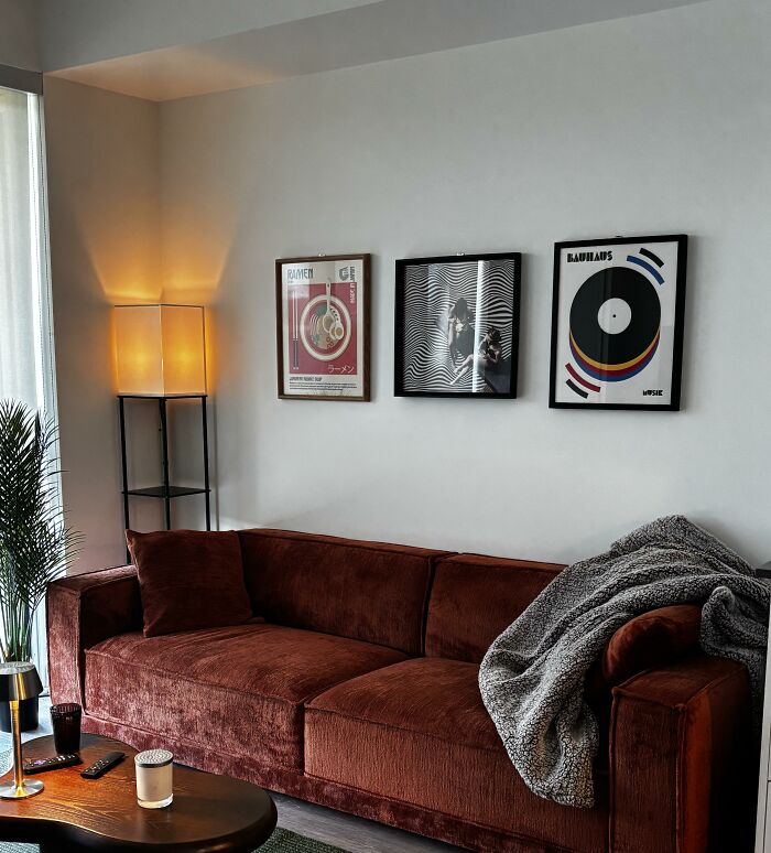 A cozy living room with a red sofa, artistic posters on the wall, and warm lighting, showcasing home design choices.