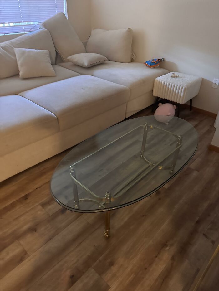 A minimalistic living room featuring a cream-colored sectional sofa and a glass coffee table, highlighting home design choices.