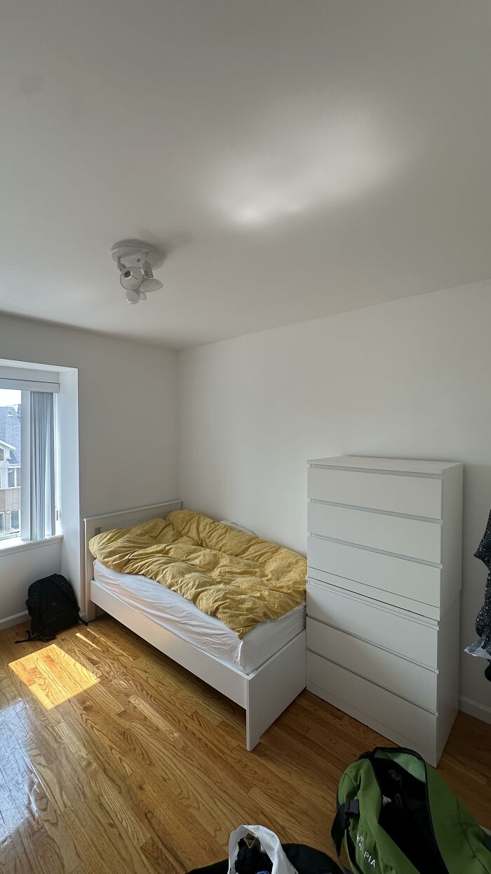 A bright bedroom with a single bed and a white dresser, featuring simple home design choices.