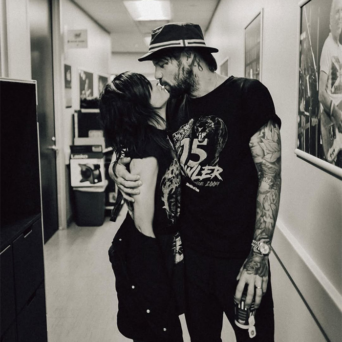Black and white image of rock star kissing a person in a hallway after coming out as gay.