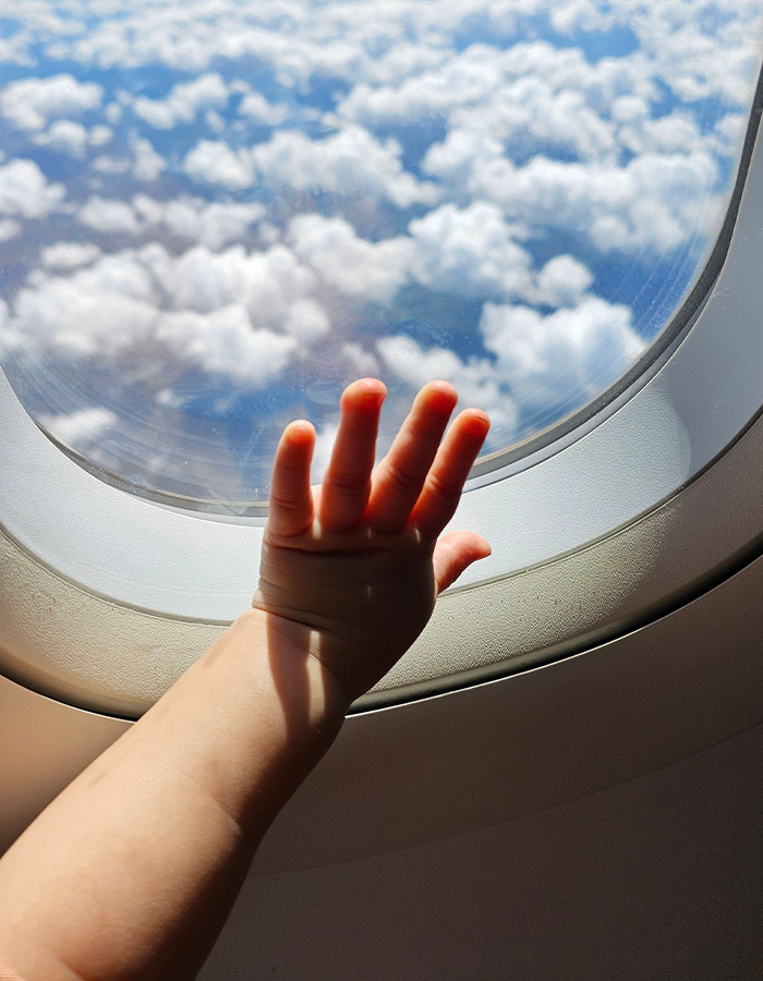 An unruly toddler's hand reaching towards an airplane window, contributing to a flight being canceled. An unruly toddler's hand reaching towards an airplane window, contributing to a flight being canceled.