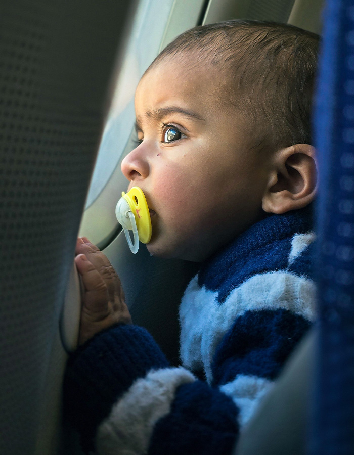 A toddler with a pacifier looking out an airplane window, a common sight before a flight is canceled. A toddler with a pacifier looking out an airplane window, a common sight before a flight is canceled.
