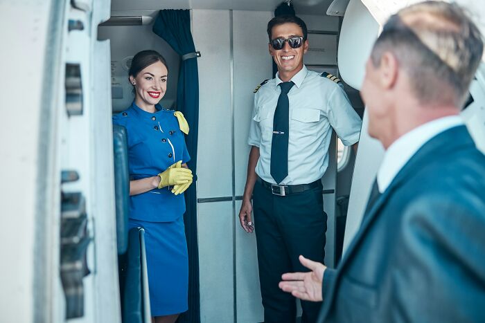 Smiling cabin crew and pilot on an airplane, ready to answer questions and provide service.