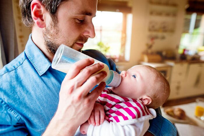 Father feeding baby, representing cabin crew facing unhinged questions from passengers.