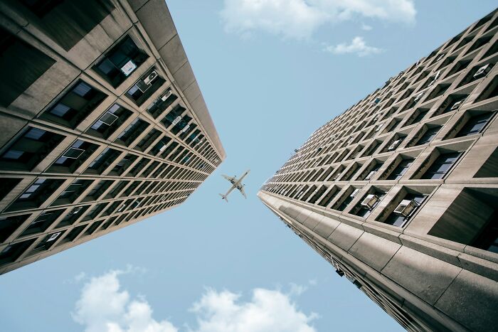 Airplane flying between two tall buildings, highlighting unhinged questions cabin crew are asked.