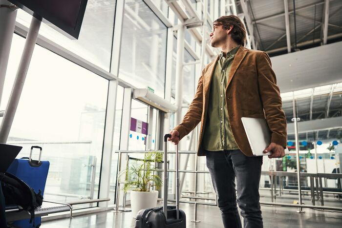 A man with a suitcase at an airport, symbolizing unhinged questions cabin crew face.