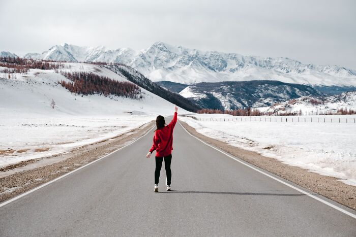 A person on a road with snowy mountains, evoking the unexpected, like unhinged questions cabin crew are asked.